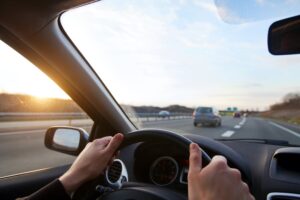 Hands on steering wheel looking out of car window
