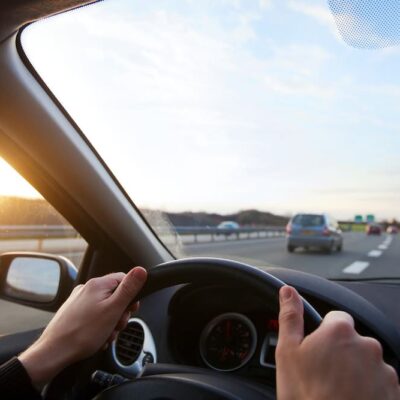 Hands on steering wheel looking out of car window